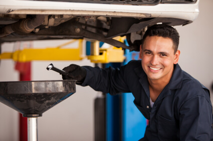 Male mechanic performing an oil-change to a car for maintenance