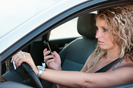 Close up to a young Caucasian woman texting and driving.
