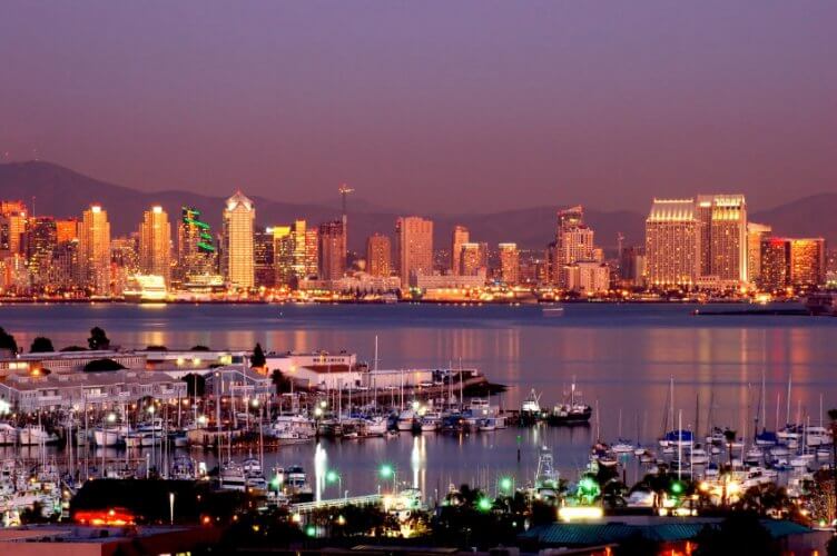 Skyline of San Diego at sunset with the bay and sailboats. Buildings in background.