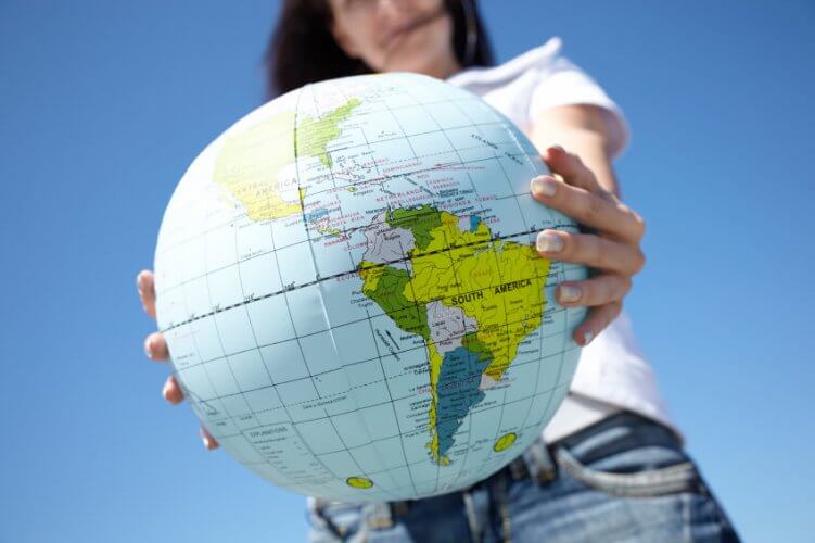 Close up to a globe held by a young woman illustrating global travel.