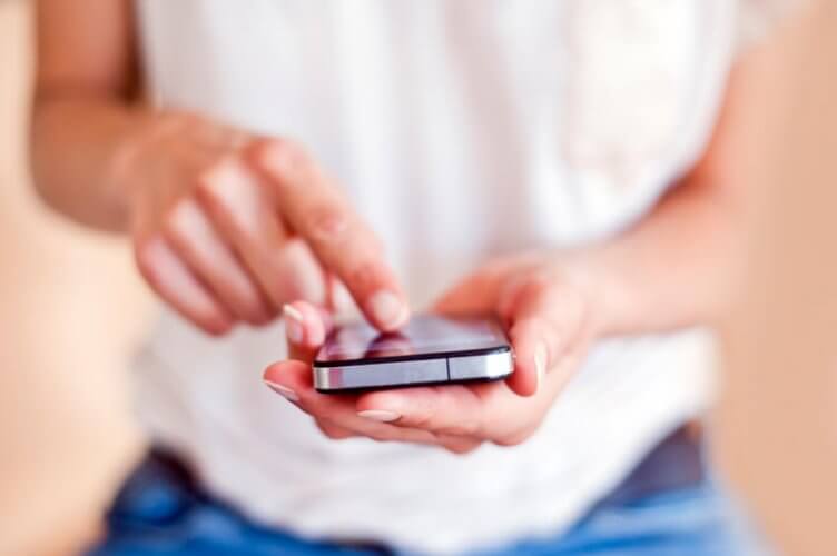 Close up to young woman's hands using a touchscreen smartphone.