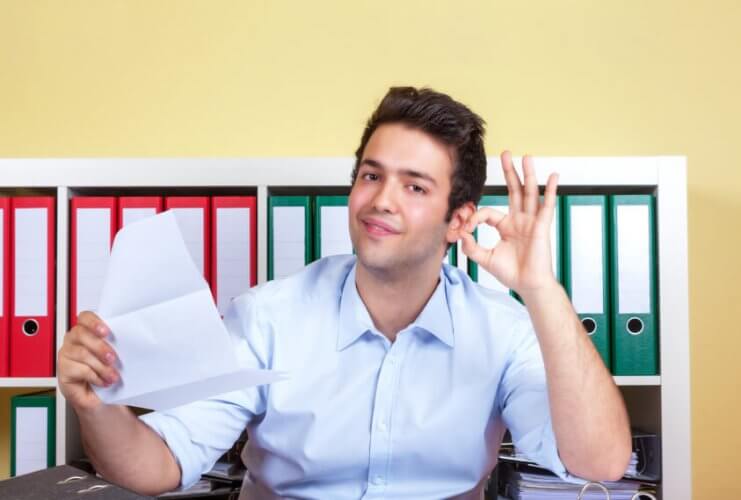 Photography of a happy young man smiling with a document on his hand.