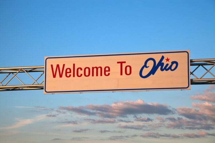 A road sign welcome to Ohio seen with the sunset in the back.