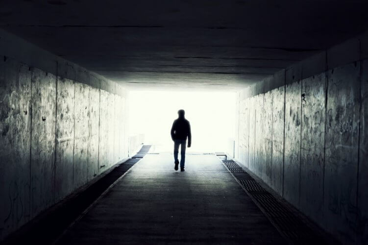 Silhouette of Man Walking in a Pedestrian Tunnel with Light in the End