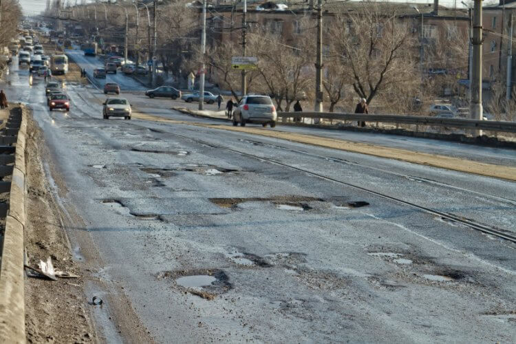 Busy road with a lot of potholes illustrating the relationship between potholes and your auto insurance