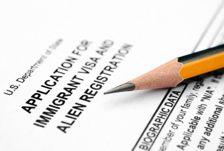 Close up to an Application for Immigrant Visa and Alien Registration form with a sharpened pencil on top to illustrate illegal immigrants' driver's license.