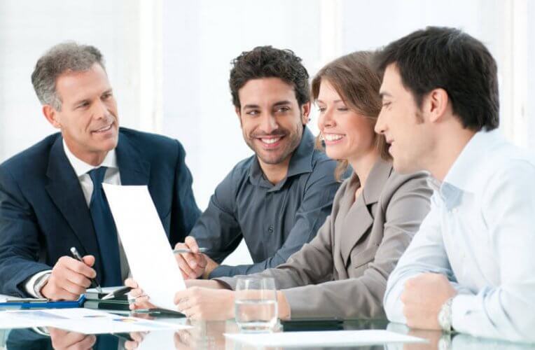 Small group of people smiling and looking at a document about California workers compensation.