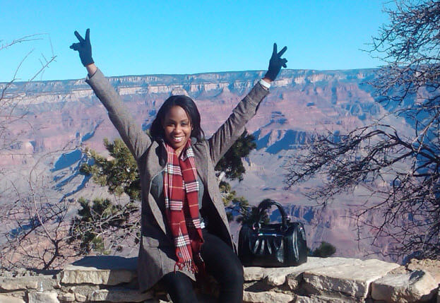 Young black woman smiling with arms up in joy with the Grand Canyon in background to illustrate Grand Canyon vacations