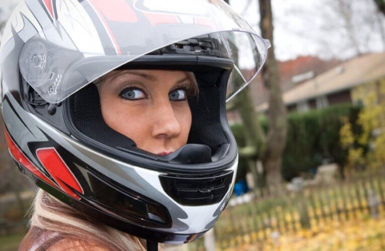 Close up to an attractive woman wearing a motorcycle helmet to illustrate motorcycle helmet history