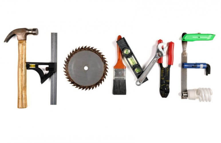 Hammer, adjustable spanner, spirit level, utility knife and other maintenance tools forming the word HOME to illustrate seasonal home maintenance tips