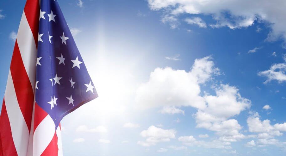 Flag of the United States of America with the sun and a blue sky as background