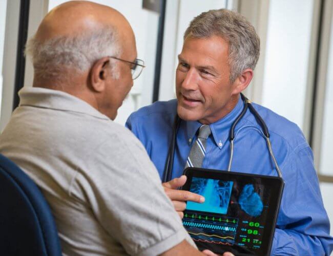 A middle aged male doctor showing an older patient his chest x-ray to portray how to find affordable health insurance in Phoenix