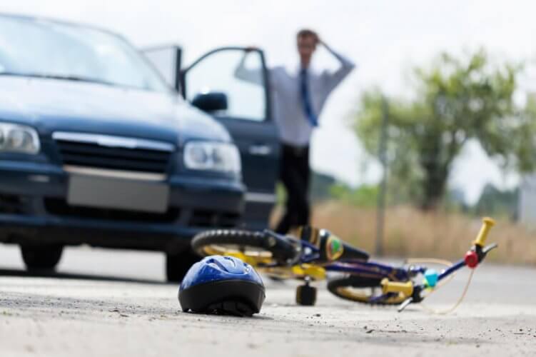 Driver outside his car looking concerned at child's bike and helmet on the road to illustrate running over a young child