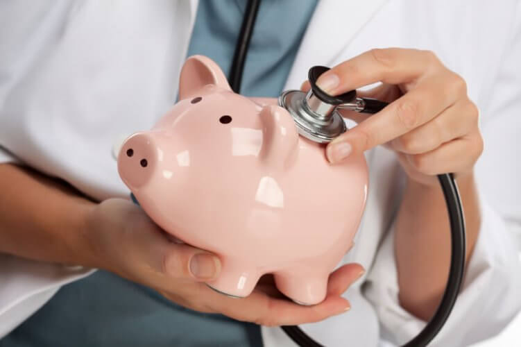Close up to a Piggy bank held by a doctor as she examines its back with a stethoscope
