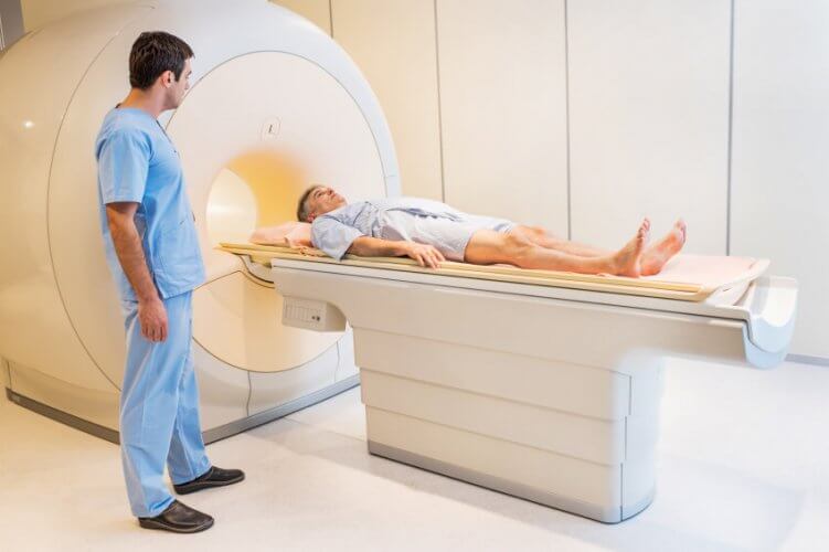An adult radiologist giving instructions to the elderly patient who is about to receive an MRI Scan,.