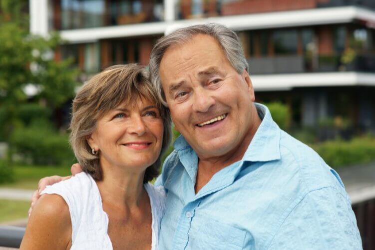 Close up to a happy senior couple relaxing together outside their apartment building