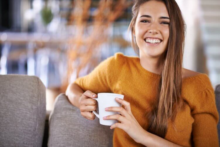 Young woman drinking coffee while sitting on the sofa