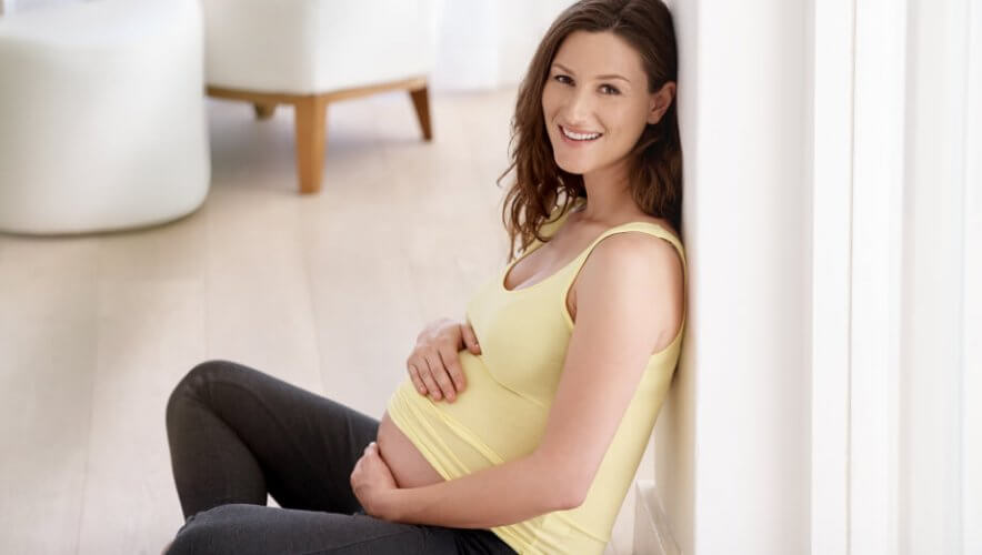 Young pregnant woman sitting on floor wearing yoga clothes
