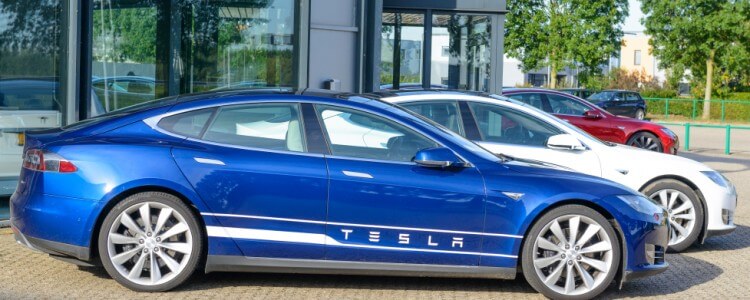 Tesla sedan car parked next to other vehicles in a parking lot.