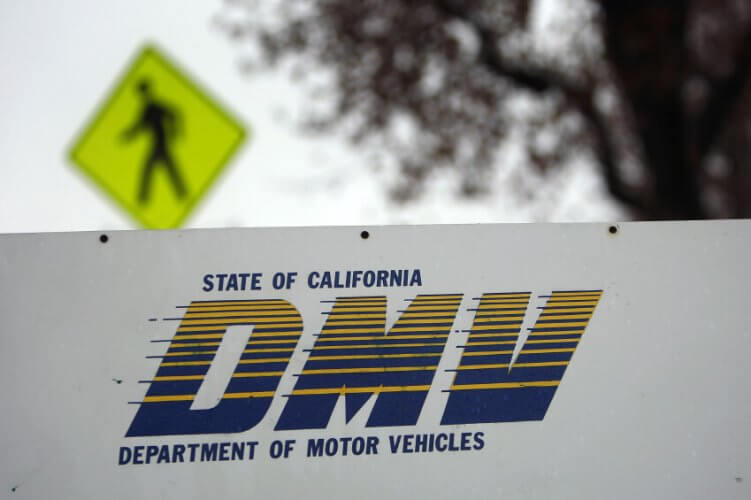 State of California DMV (Department of motor vehicles) signage. Pedestrian road sign behind.