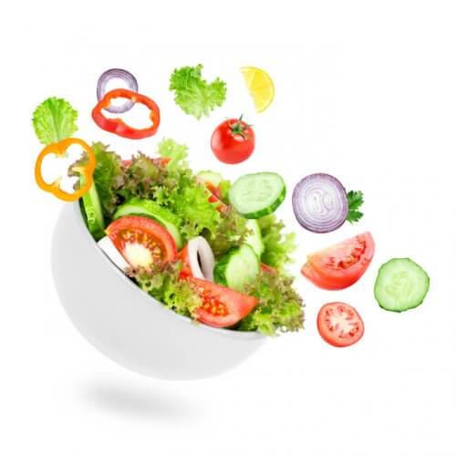 Mixed vegetables for a salad falling in bowl. Chopped lettuce, onions, tomato, paprika and cucumber.