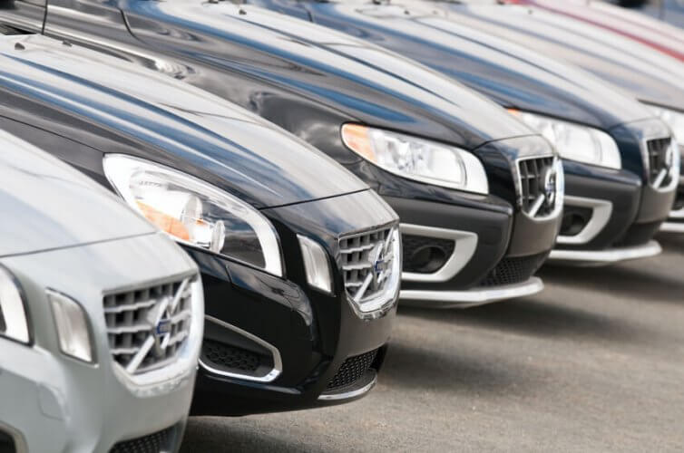 Row of Volvo cars parked in a parking lot.