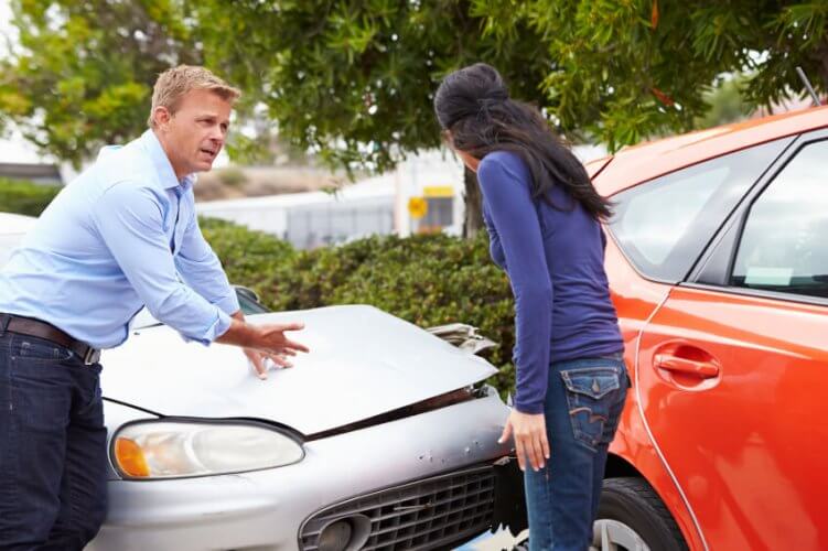 Car crash. Owners of cars (man and woman) argue about their car's damages and whether they have car insurance.