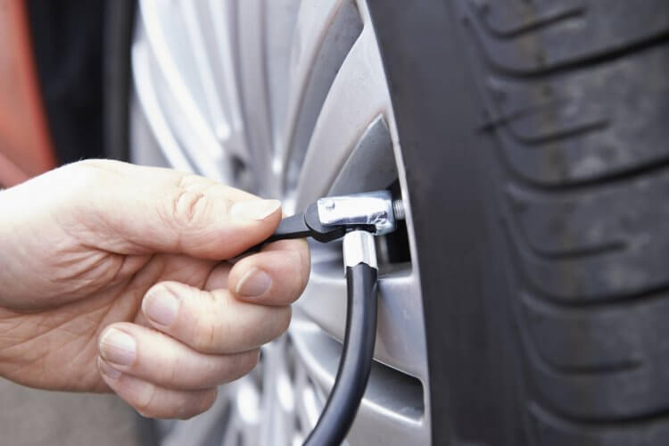 Close Up Of Man's Left Hand Inflating Car Tyre With Air Pressure Line