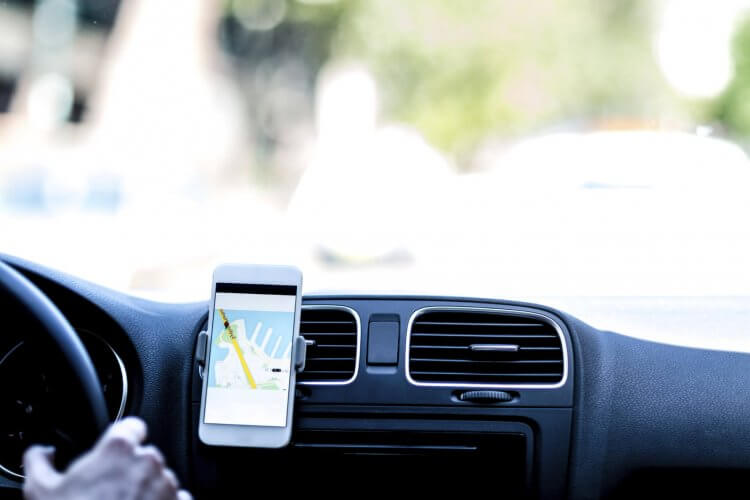 Close up to AC vents of a car in which a smartphone with navigation app is attached.