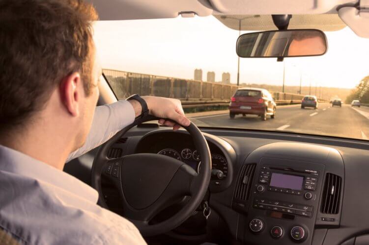 A man driving in a sunny day to illustrate how Is State-Minimum Car Insurance Getting Too Expensive