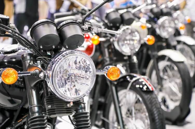 Line of similar motorcycles. Close up to the first motorcycle headlight.