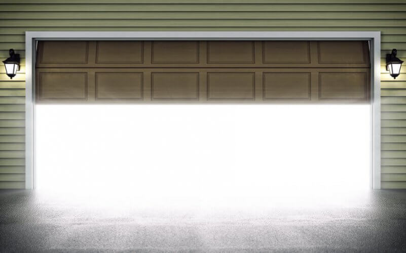 Picture of a garage door half open. A lot of light coming through. One vintage street lantern on each side of door.