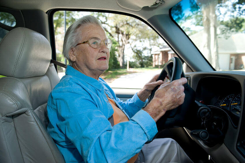 Elderly driver who cannot see the road sign well - Stock Photo