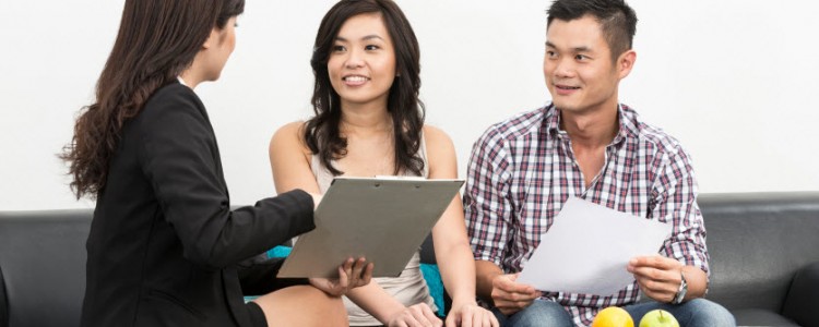 Young female car insurance agent showing and explaining the policies to a smiling asian couple