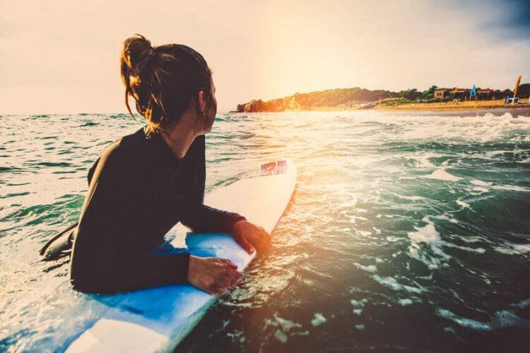 A woman floating on her surfboard illustrating the Insurance You'll Need Thinking of Taking Up Surfing