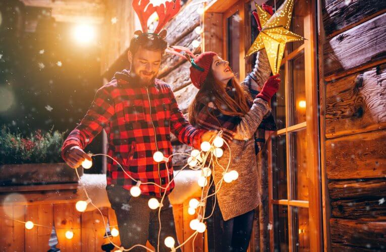 A young couple wearing reindeer antler headbands decorate for Christmas.