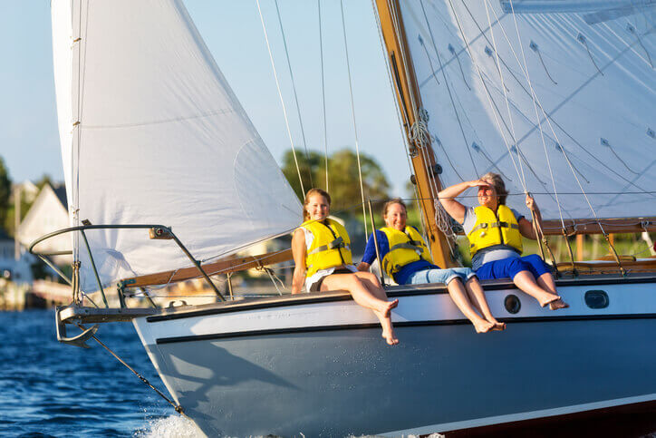 A group of women wearing safety vests and sitting on a yacht to illustrate watercraft insurance