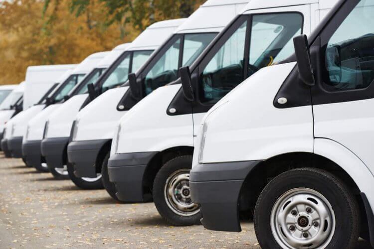 Row of commercial delivery vans parked in front of business building