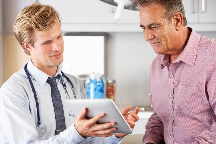 Doctor Discussing Health Records With Patient Using Digital Tablet to showcase if immigrants qualify for California healthcare