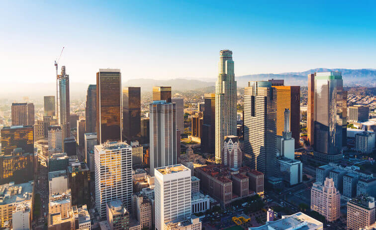 Aerial view of a Downtown Los Angeles at sunset showing high buildings and roads.