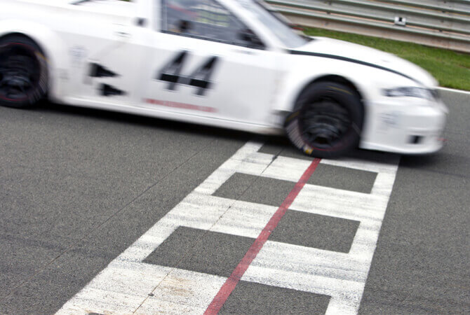 A car with the number 44 on its side crosses finish line of Nascar race to illustrate Nascar contributions to US automakers and your safety