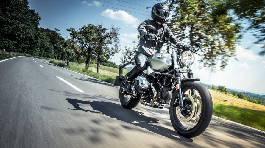 Fully equipped biker speeding on his motorcycle on an empty road.