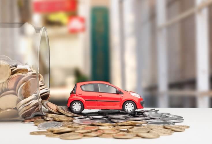 Toy car on top of a bunch of coins that have fallen out of a tilted jar.