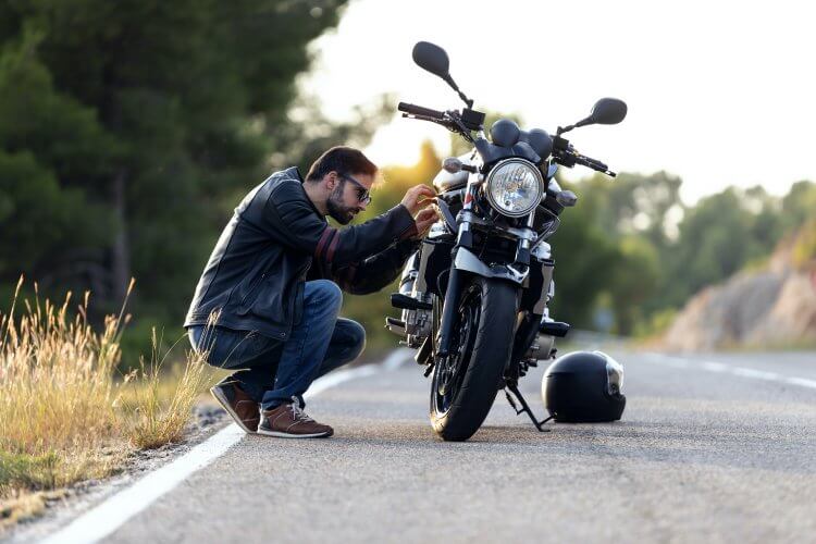 Photography of male biker checking his motorbike before driving it on the road