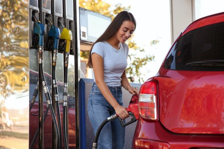 Young woman refueling car at self service gas station