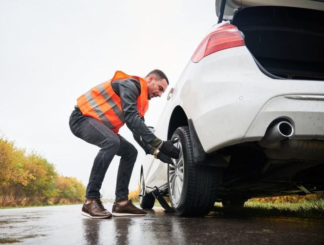 Roadside assistance worker removing flat tire while repairing car on the street - How to Save on Roadside Assistance With Freeway Auto Club - Freeway