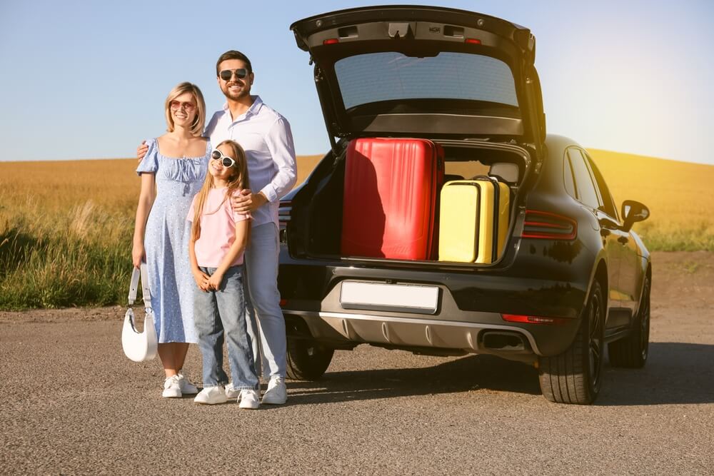 Familia junto a un auto con maletas listas para un viaje por carretera, ilustrando los requisitos para viajar en Estados Unidos en carretera.