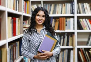 Estudiante con libros en una biblioteca explorando opciones de carreras cortas en USA para latinos.