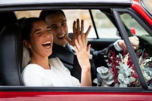 Pareja recién casada celebrando dentro de un auto después de su boda en Estados Unidos.