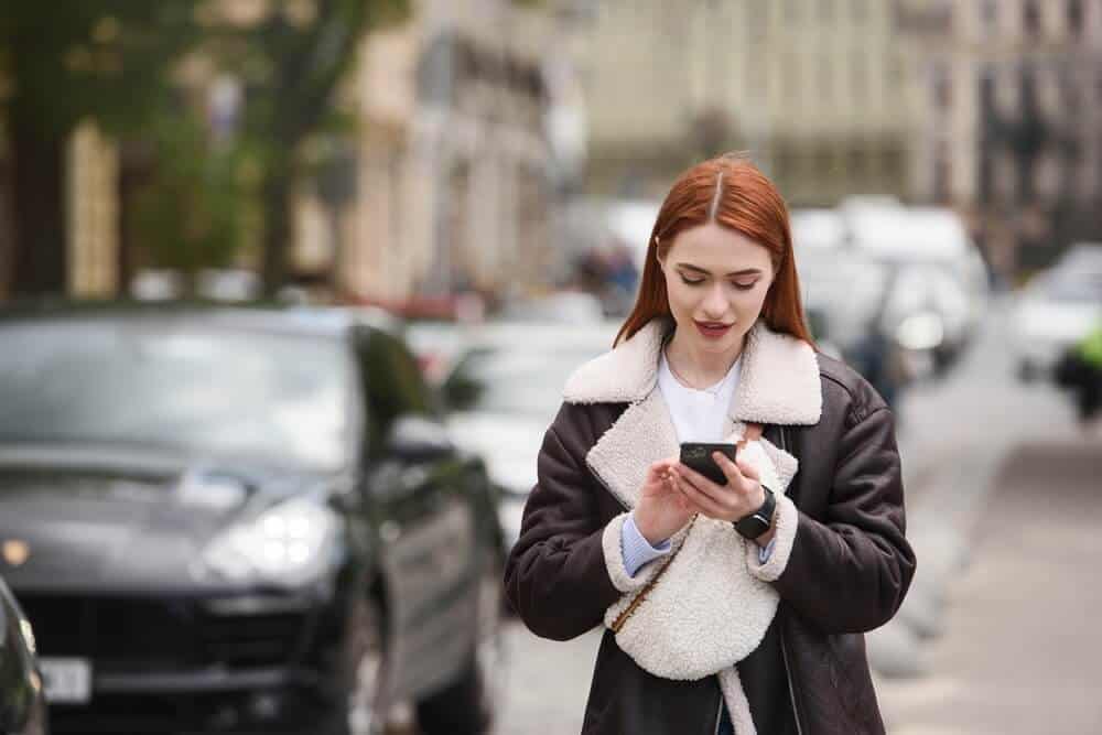 Persona revisando su teléfono y documentos, representando los requisitos para manejar con Uber o Lyft.